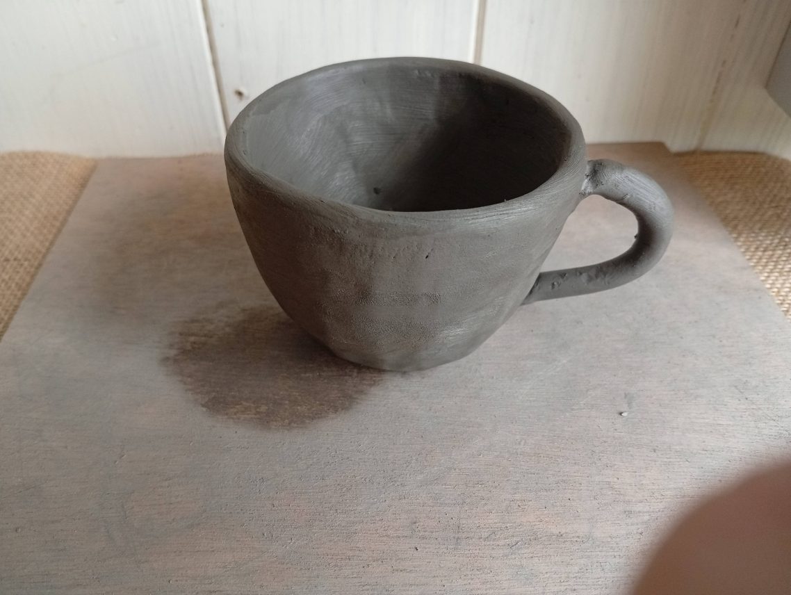 Tasse modelée avec anse Tasse en argile non cuite, avec un design simple et une poignée.