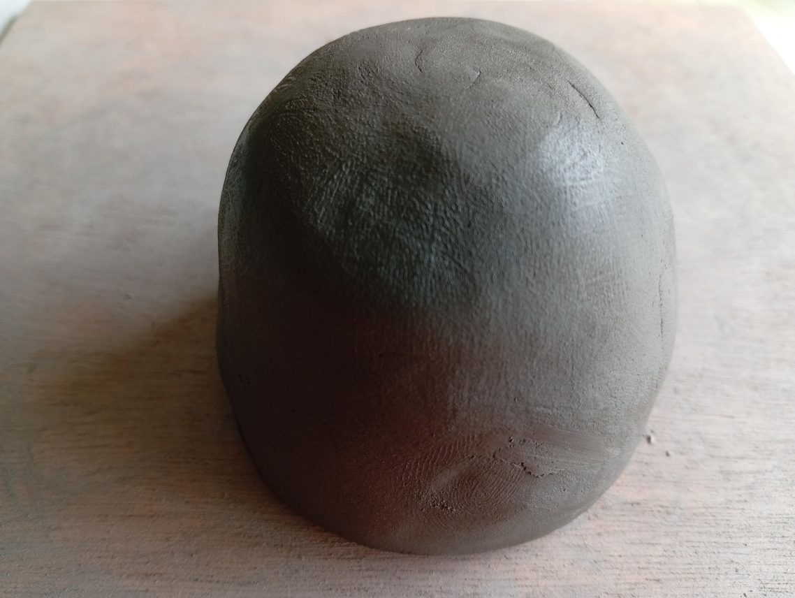 Boule d'argile (grès) Boule de pâte grise, lisse, sur une surface en bois.