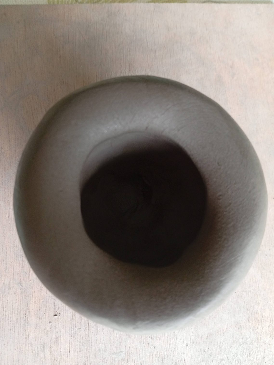 Perçage de la poterie Vase en céramique de forme arrondie, couleur grisâtre, vue du dessus.